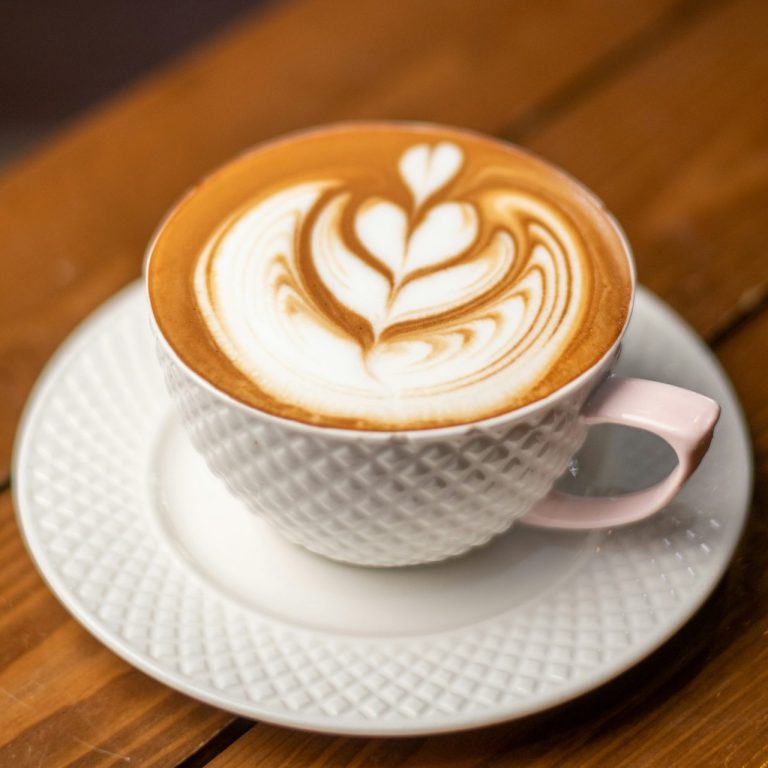 Eine Tasse Latte Art mit Herzmuster auf einem Holztisch.