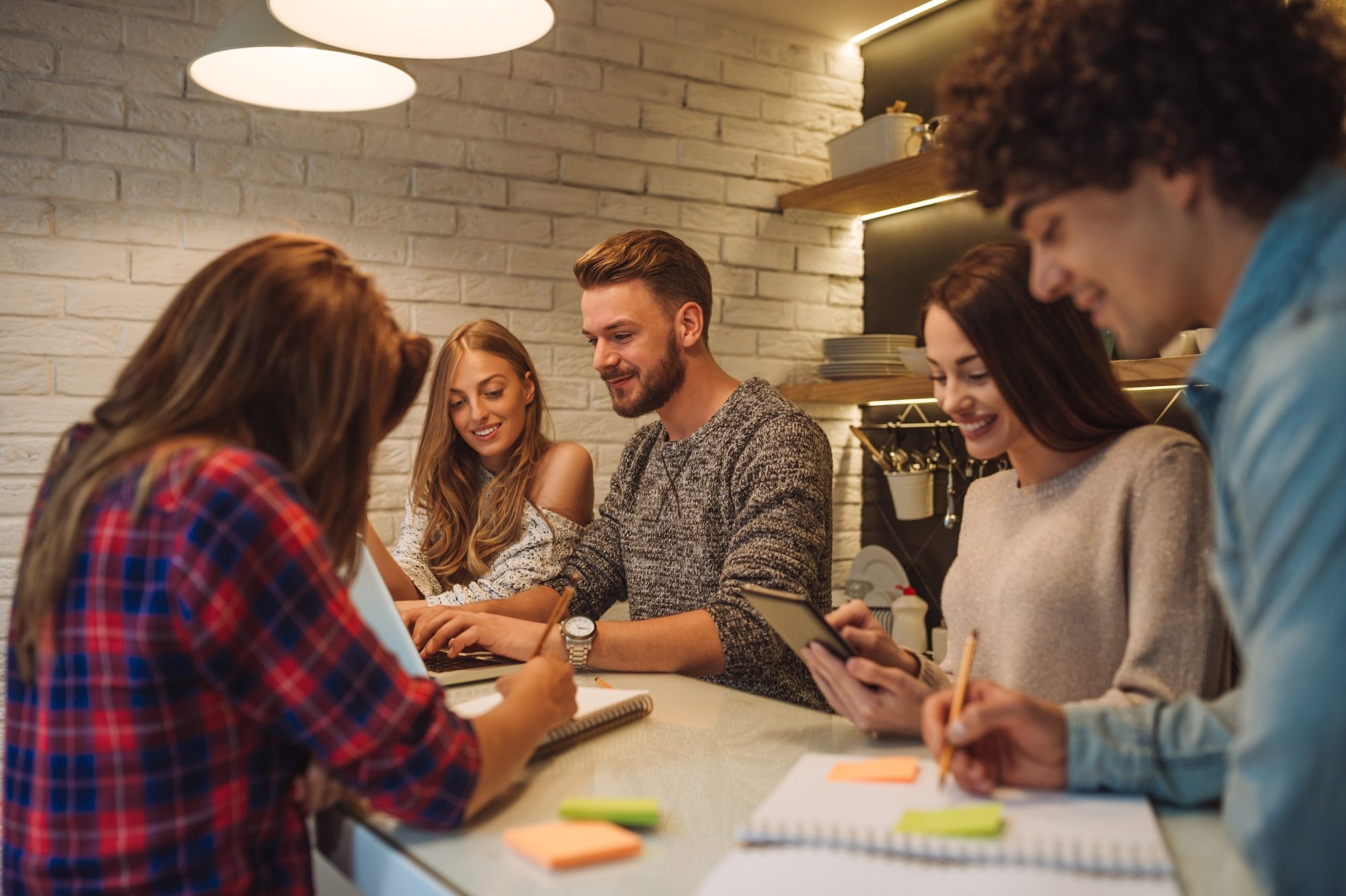 Gruppe von fünf Personen, die an einem Tisch an einem Projekt arbeiten und Notizen machen.