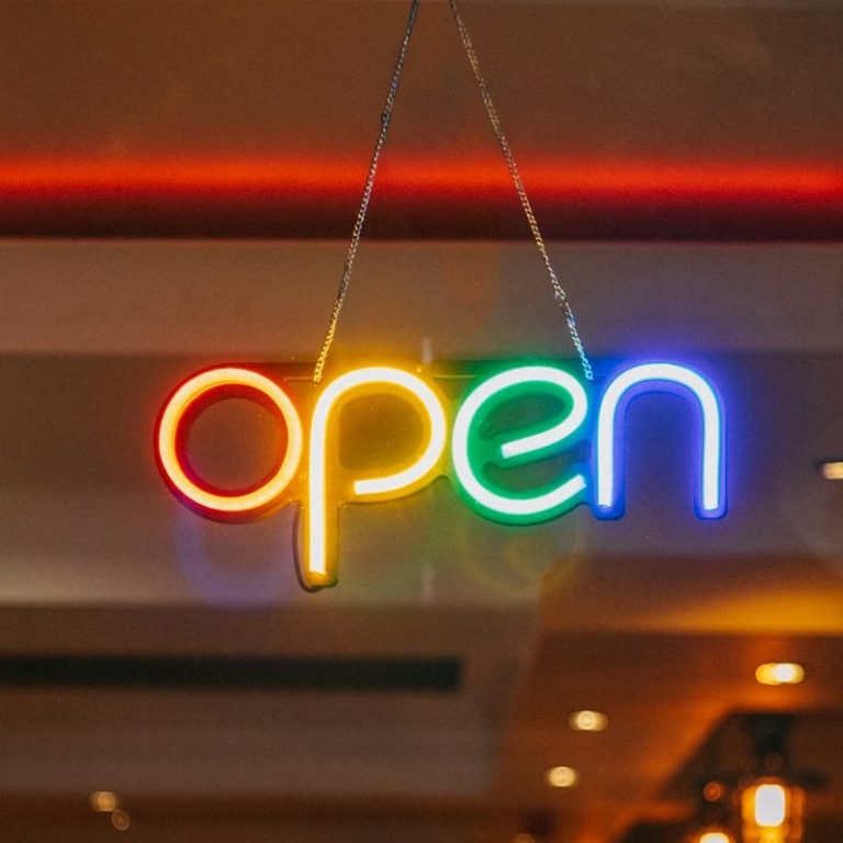 Leuchtschild mit der Aufschrift "open" in bunten Neonfarben.